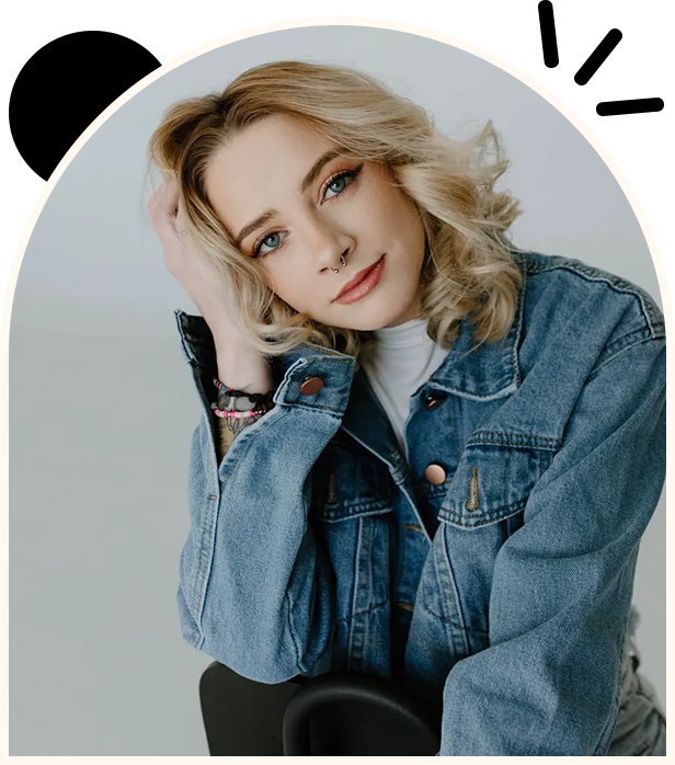 A woman in blue jean jacket sitting on top of a chair.