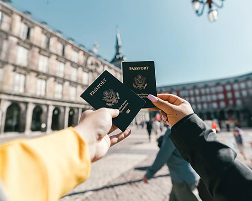 Two people holding up their passports in a city.