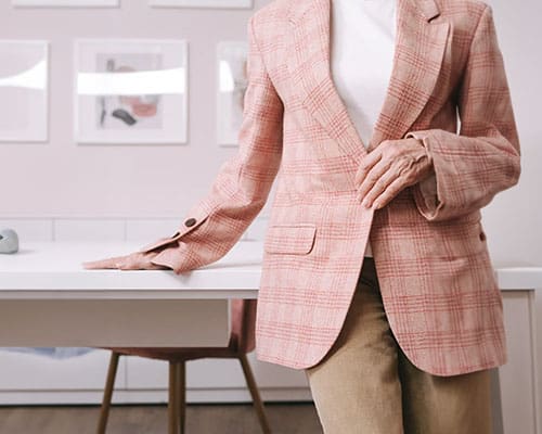 A woman in pink jacket and beige pants.