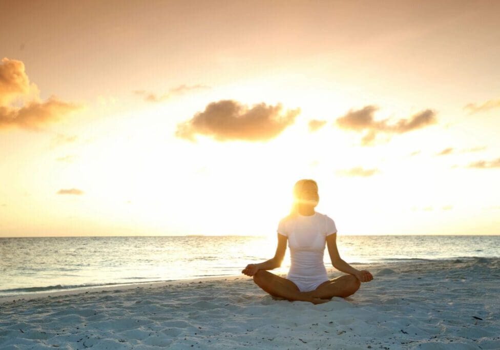 A person sitting in the sand on top of a beach.